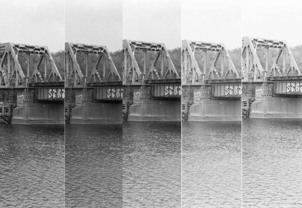 Five distinct black and white photos of a steel bridge truss that crosses the Mississippi River. The light levels and shadows go from darkest to lightest from left to right.