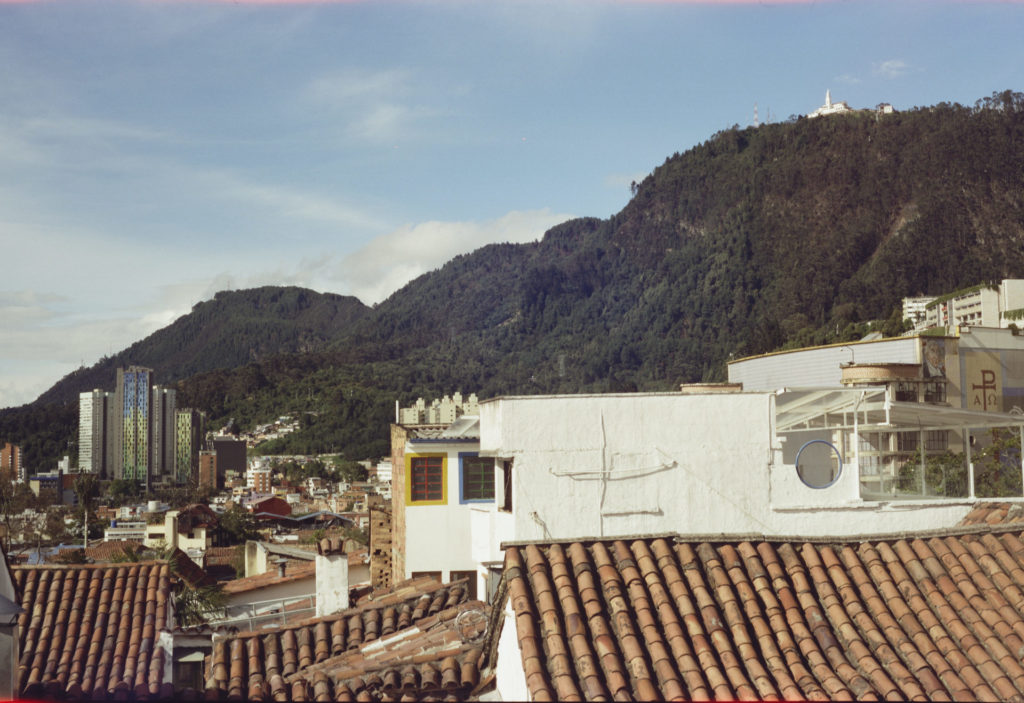 A color photo of Bogota. The old Candelaria neighborhood, part of a newer highrise and the maintains.