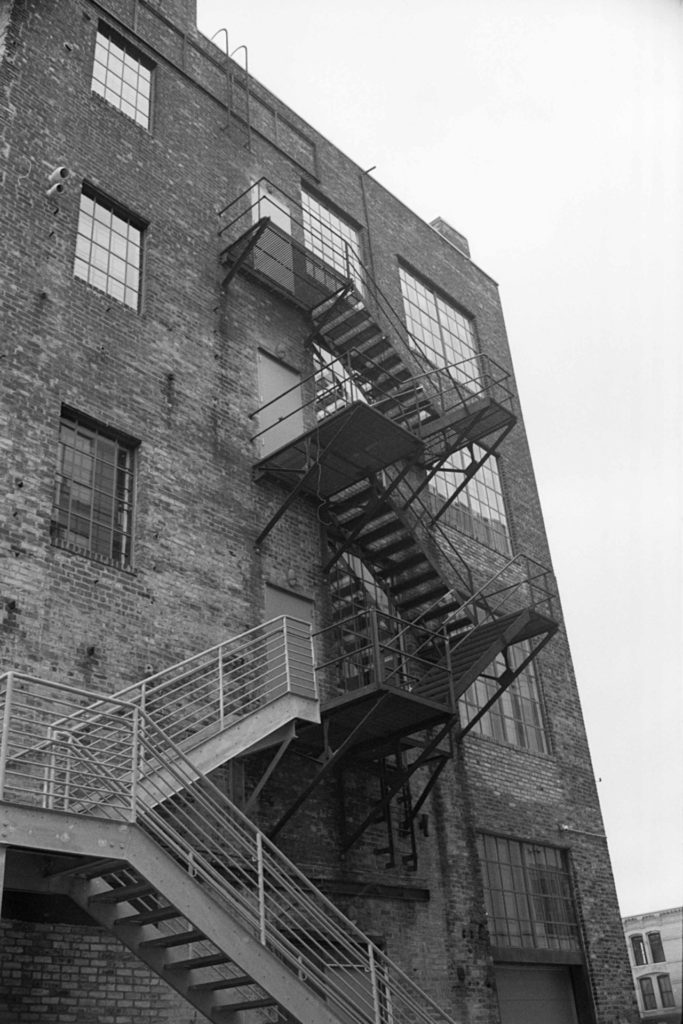 A black and white photo of a set of fire escape stairs on the back of a brick building in the North Loop neighborhood of Minneapolis
